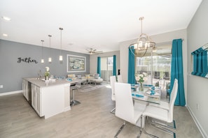 A modern kitchen with white cabinetry, a central island, and pendant lighting. - Luxury Resort 4BD Home W/Private Pool Near Disney (Kissimmee)