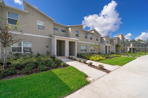 A residential building with a modern design, featuring a covered entrance, a well-maintained lawn, and a clear sky. - Luxury Resort 4BD Home W/Private Pool Near Disney (Kissimmee)