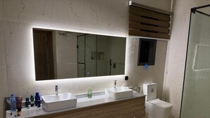 Une salle de bain avec un grand miroir, deux lavabos, une douche et des toilettes.
