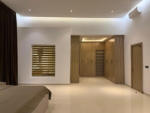 Een moderne slaapkamer met een bed, een raam met jaloezieën, een kast en een deur.