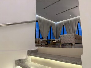 A modern interior with a staircase, a dining area with a table and chairs, and a view through large windows. - 3 bedroom all ensuite split level luxury penthouse with skyline views over Abuja (Abuja)
