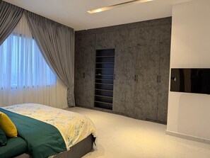 Ein modernes Schlafzimmer mit Bett, Kleiderschrank und integriertem Fernseher.