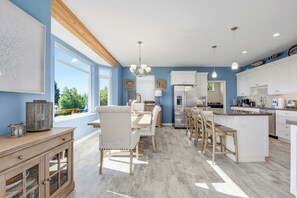 A spacious kitchen with a central island, white cabinetry, and a large window providing a view of the outdoors.