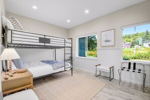A bunk bed room with a desk, chair, and a window with a view of greenery. - Spacious home w full Kachemak Bay views (Homer)