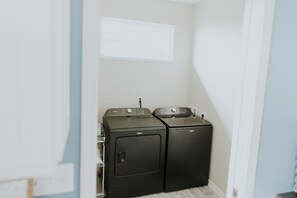 A laundry room with two stacked front-loading washers and dryers. - Spacious home w full Kachemak Bay views (Homer)