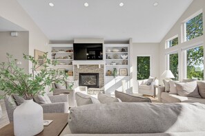 A modern living room with a fireplace, built-in shelves, and a large window.