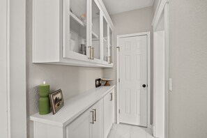 A hallway with white cabinets, a door, and a small table with a candle and picture frame.