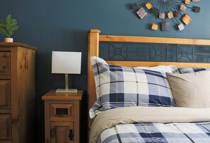 A bedroom with a wooden headboard, a bedside table with a lamp, and a decorative wall piece.