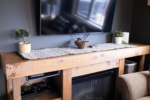 A wooden entertainment center with a television mounted above it, a small potted plant, and a woven placemat.