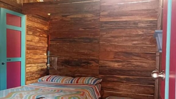 A wooden cabin room with two beds, a door, and a window.