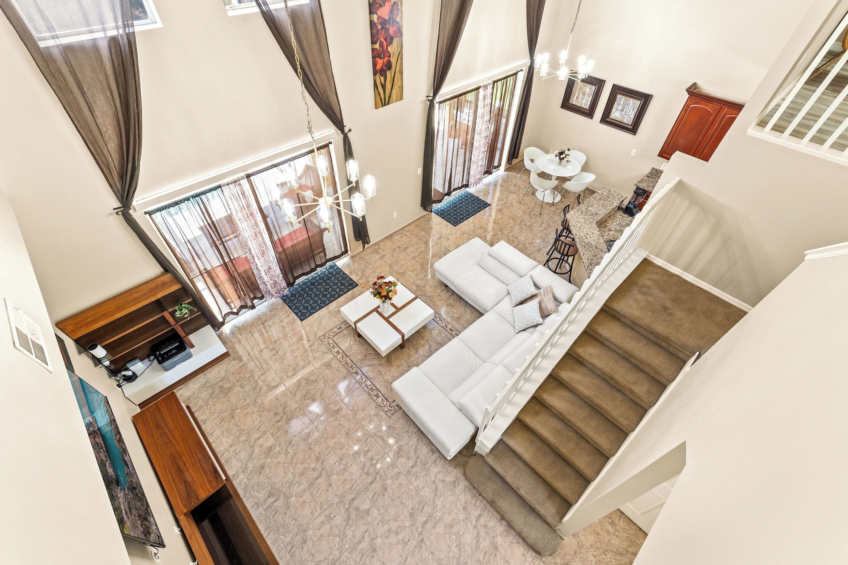 Un espacio habitable amplio con un juego de sofá, una mesa de centro y una mesa de comedor con sillas. Una escalera conduce a un piso superior.