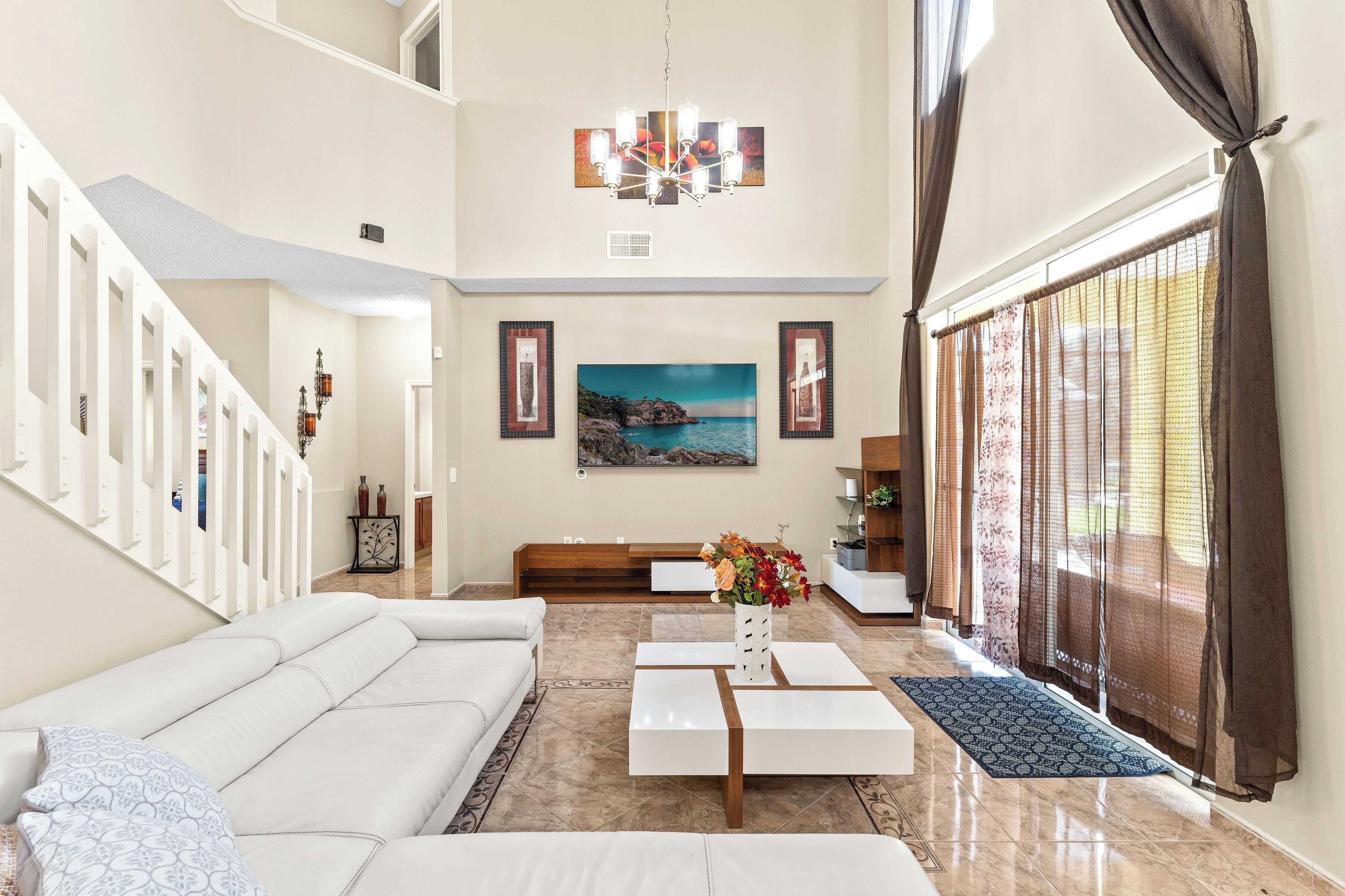 A spacious living room with a white sofa, a coffee table, and a painting on the wall.