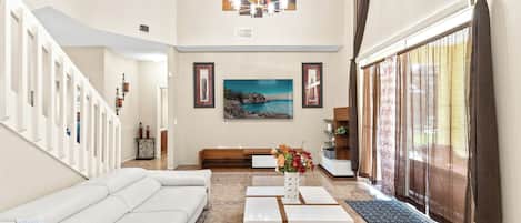A spacious living room with a white sofa, a coffee table, and a painting on the wall.
