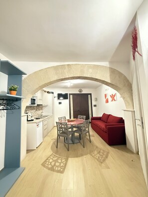 A compact living space with a dining area, kitchenette, and a red sofa. - Cozy studio in the historic center of Trapani (Trapani)