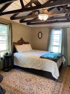 Ein Schlafzimmer mit einem Bett, einem runden Spiegel und einer Chandelüster.