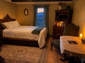 Ein Schlafzimmer mit einem Bett, einem Schreibtisch, einem Stuhl, einer Kommode und einem Fenster mit Blick.
