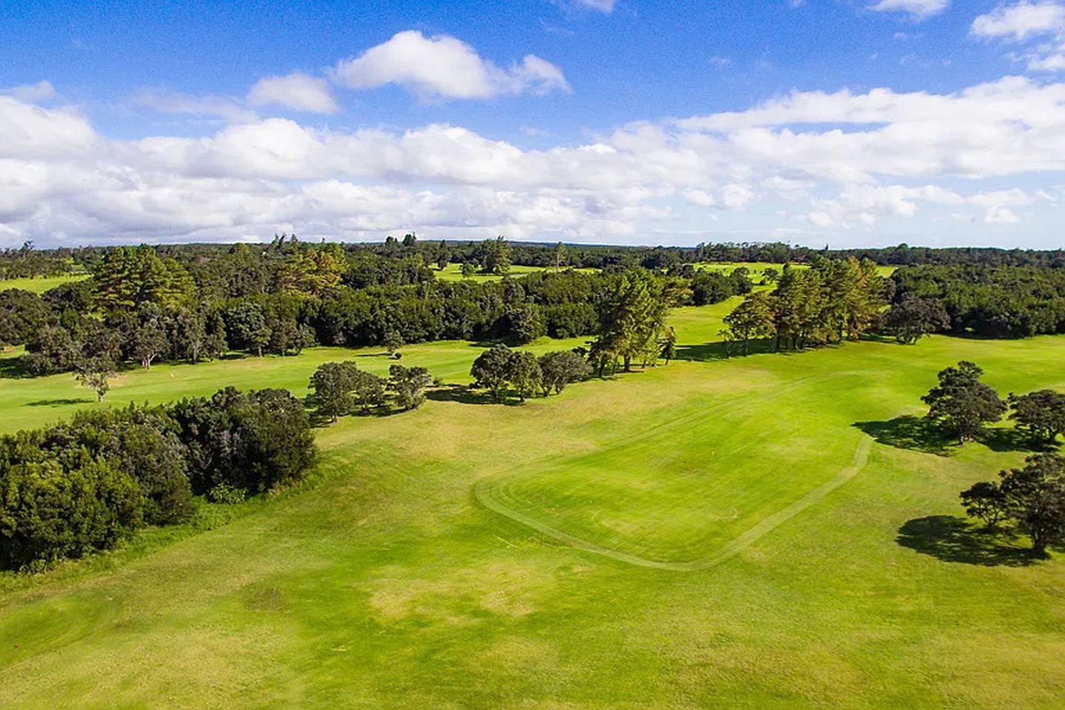 Un terrain de golf sous un ciel dégagé, parsemé de quelques nuages.