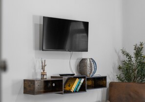 Een flatscreen televisie bevestigd aan een muur boven een houten console met boeken en decoratieve objecten.
