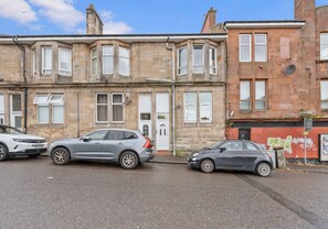 A row of terraced houses with a street in front. - Modern ground floor apartment close to train station (Coatbridge)