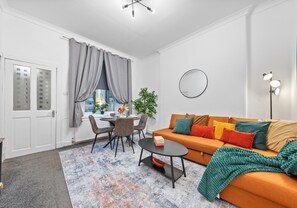 Een moderne woonkamer met een bank, salontafel en een eethoek.