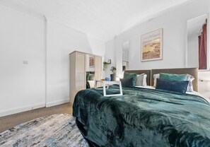 Ein Schlafzimmer mit einem großen Bett, einem Nachttisch, einer Kommode und einem Bild an der Wand.