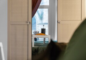 A room with a door leading to a balcony. On the balcony, there is a table with a cup and a pastry. - Modern ground floor apartment close to train station (Coatbridge)