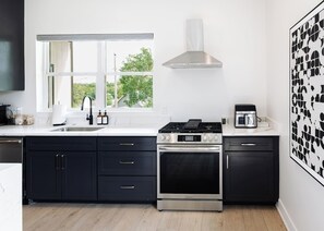 A modern kitchen with a built-in oven, a microwave, and a gas stove. - The Clubhouse | Ultimate Golf & Game House (Kansas City)