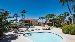 A resort pool area with lounge chairs and a building with a red-tiled roof. - Waikoloa Beach Resort 2BR Suite, Private Lanai – The Bay Club by HGV (Waikoloa Village)