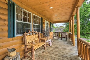 A wooden cabin with a porch, a bench, and a rustic firewood block.