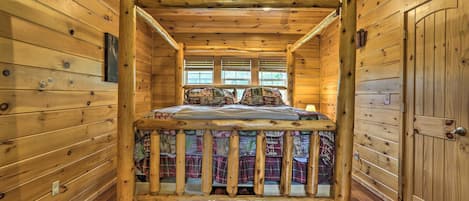 Una habitación de cabaña de madera con una cama, un ventanal y una puerta.