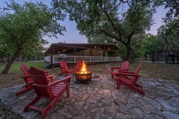 A stone patio with a fire pit and red Adirondack chairs. - Austin 5BR - Pool & Spa - Games - Indoor Fire (Austin)