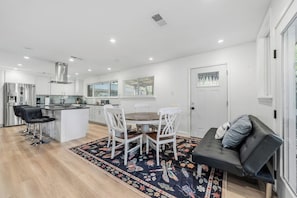 A modern kitchen with white cabinetry, a central island, and bar stools. - Austin 5BR - Pool & Spa - Games - Indoor Fire (Austin)