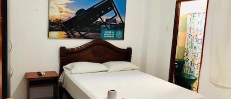Una habitación de hotel con una cama, una mesita de noche, un aire acondicionado de pared y un cartel.