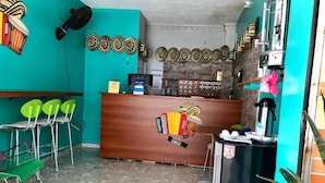 A reception area with a wooden counter, green chairs, and a coffee machine. - Hotel Casa Martina Valledupar (Valledupar)