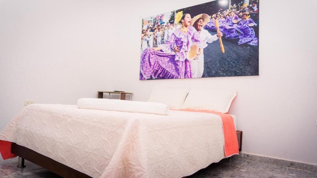 Una habitación de hotel con una cama, una mesita de noche y un cuadro colgado en la pared.