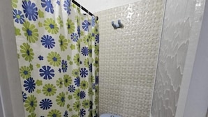 A small bathroom with a toilet, a shower curtain, and a tiled wall. - Hotel Casa Martina Valledupar (Valledupar)