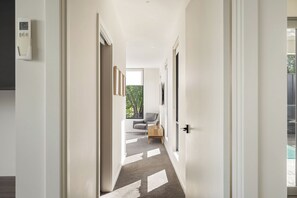 A modern hallway with a carpeted floor, a door on the right, and a window at the end. - Quindy Acre - Sleek Poolside Escape by Geographe Bay (Dunsborough)