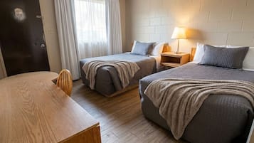A hotel room with two beds, a wooden desk, a nightstand with a lamp, and a door marked with the number 403.