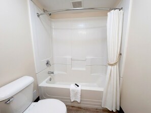 Ein kleines, weißes Badezimmer mit Badewanne, Toilette und Handtuchhalter.