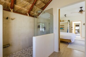 A room with a glass shower enclosure, a bed with white bedding, and a wooden ceiling. - Suite 4: Exquisite Luxury by the Sea (Los Barriles, Baja California Sur)