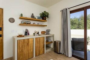 A modern kitchen with wooden cabinets, a built-in sink, and a window with curtains. - Suite 4: Exquisite Luxury by the Sea (Los Barriles, Baja California Sur)