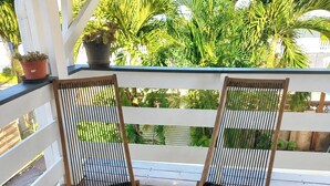 Two wooden chairs with black and white striped cushions on a wooden deck, with a woven mat in front.
