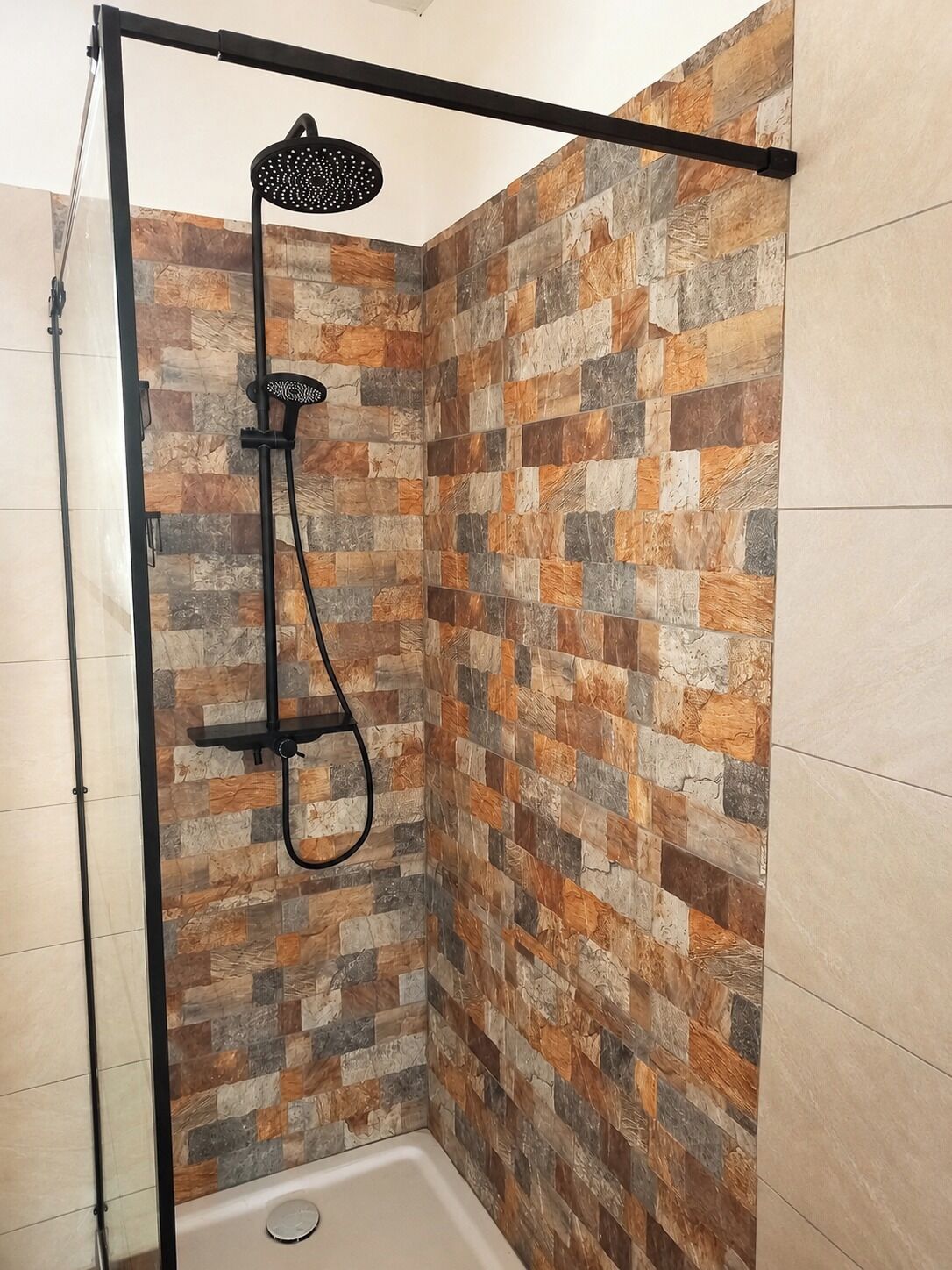 Une cabine de douche avec un cadre noir et une pomme de douche à pluie.