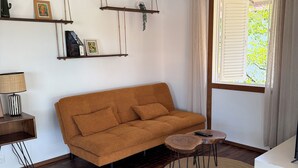 A living room with a sofa, a coffee table, a lamp, a ceiling fan, and a window with curtains.