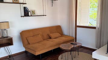 Un salon comprenant un canapé, une table basse, une lampe, un ventilateur de plafond et une fenêtre avec des rideaux.
