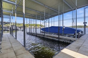 Ett avskärmat område vid bryggan med en vattenkanal, en metallkonstruktion och en blå presenning över en båt.