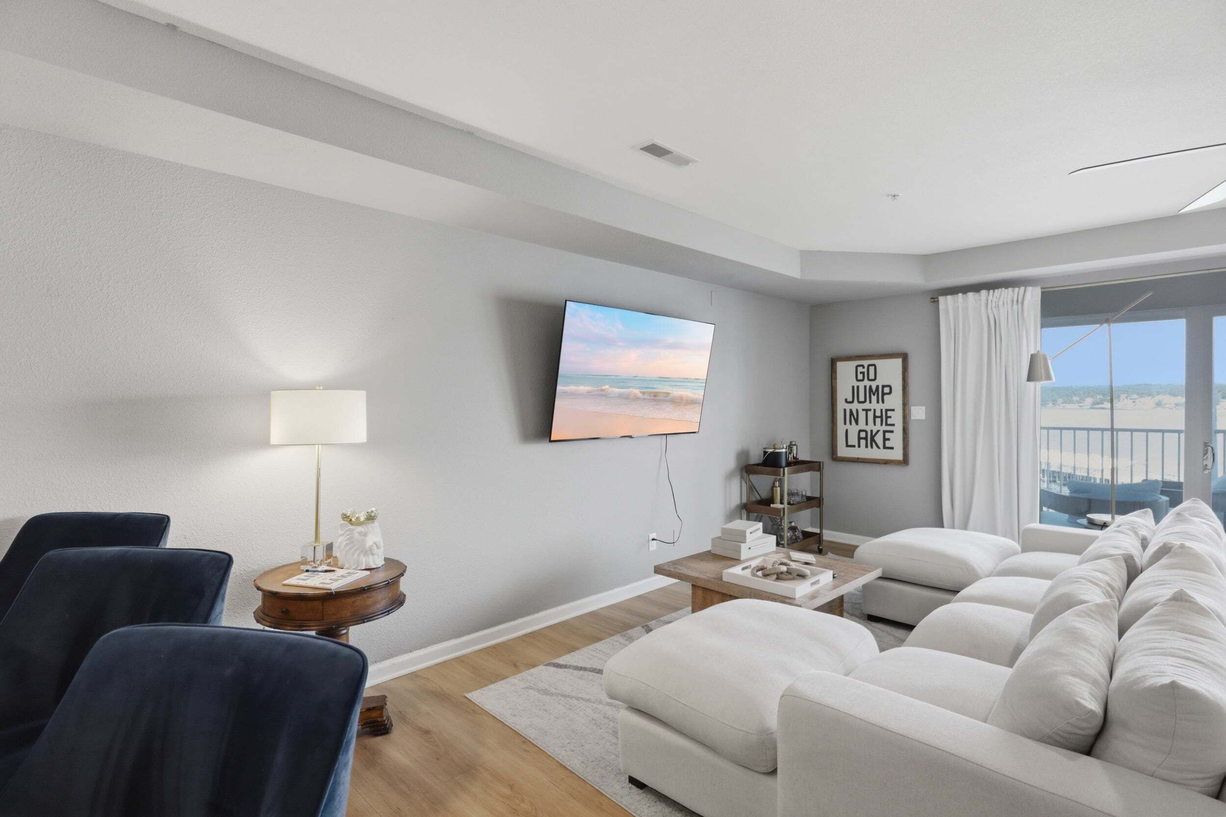 A modern living room with a sofa set, a television, a lamp, and a framed motivational quote on the wall.