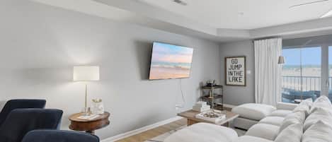 A modern living room with a sofa set, a television, a lamp, and a framed motivational quote on the wall.