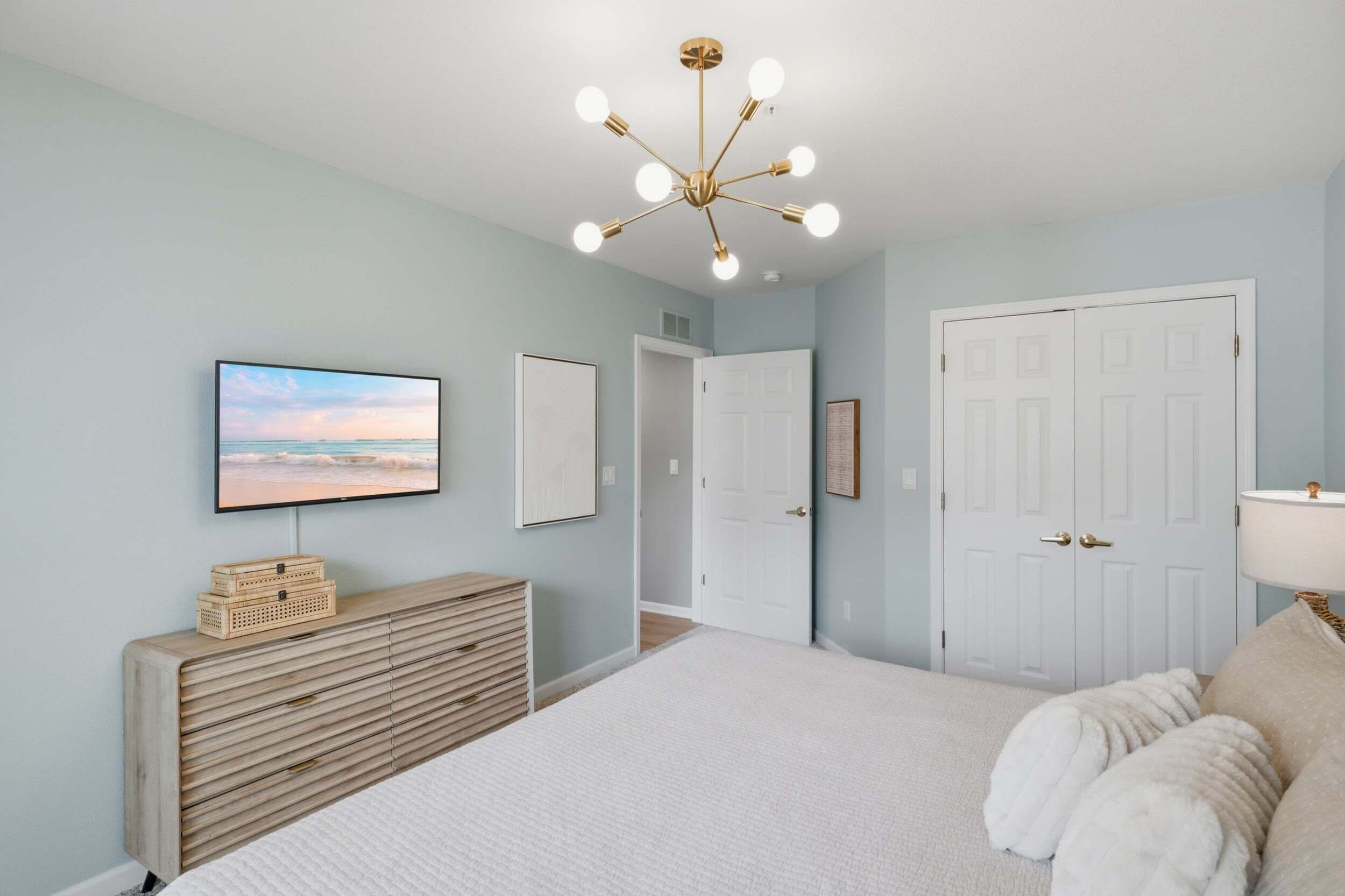 A bedroom with a bed, a television, a dresser, and a door.