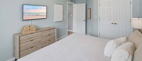 A bedroom with a bed, a television, a dresser, and a door.